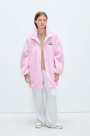 Person wearing a pink jacket with a visible brand logo on a white background