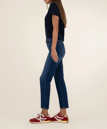 Person wearing blue jeans and red sneakers on a plain background