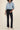Person wearing a light blue denim shirt and black pants on a beige background