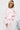 Woman wearing a pink pajama set with heart patterns on a light background