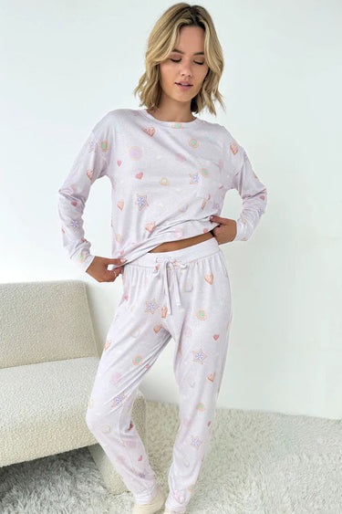 Woman wearing a white pajama set with heart patterns in a minimalistic room.