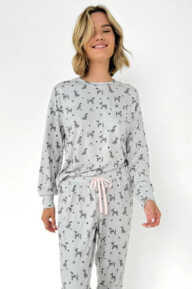 Woman wearing a gray pajama set with dog pattern on a white background