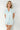 Woman wearing light blue pajama set against a white background
