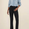 Person wearing a light blue denim shirt and black pants on a beige background