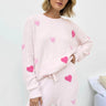 Woman wearing a pink pajama set with heart patterns on a light background