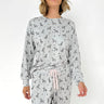 Woman wearing a gray pajama set with dog pattern on a white background