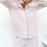Person wearing a white pajama set with red polka dots on a white background