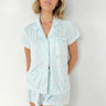 Woman wearing light blue pajama set against a white background